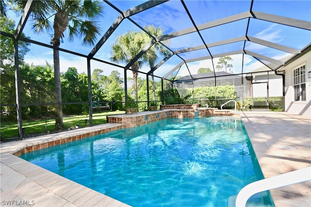 view of pool with glass enclosure, a patio area, and pool water feature