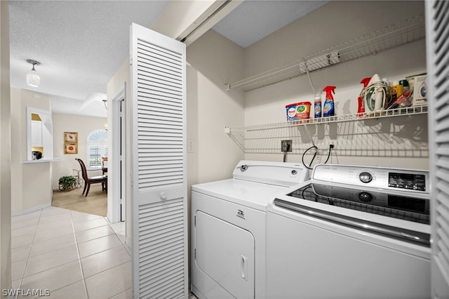 washroom with a textured ceiling, separate washer and dryer, an inviting chandelier, and light tile patterned floors