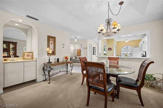 carpeted dining area with a chandelier