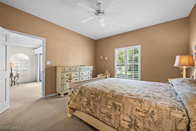 bedroom featuring ceiling fan, light colored carpet, and a textured ceiling