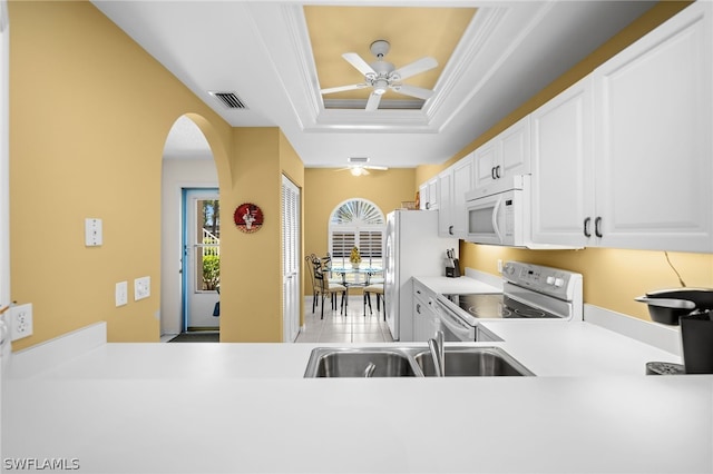 kitchen with ceiling fan, white cabinets, a raised ceiling, ornamental molding, and white appliances