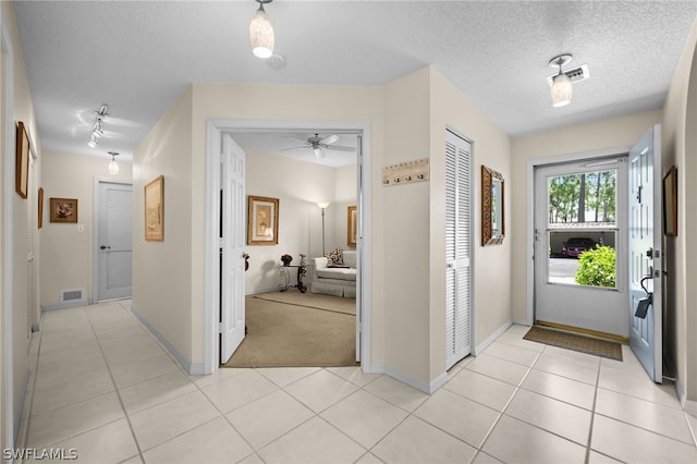 tiled foyer entrance with ceiling fan, a textured ceiling, and rail lighting