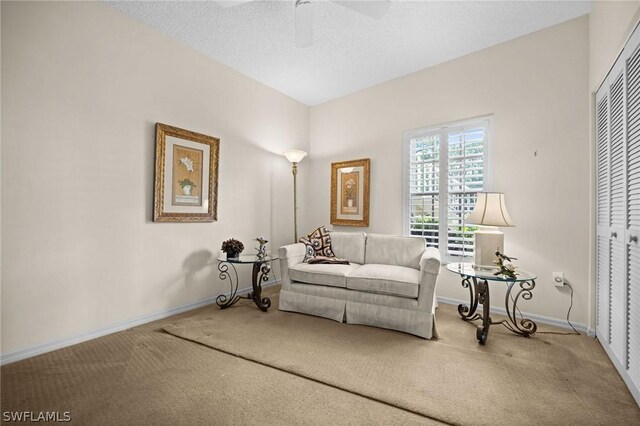 carpeted living room with ceiling fan and a textured ceiling