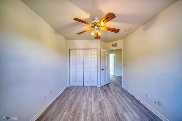 unfurnished bedroom featuring wood-type flooring, a closet, and ceiling fan