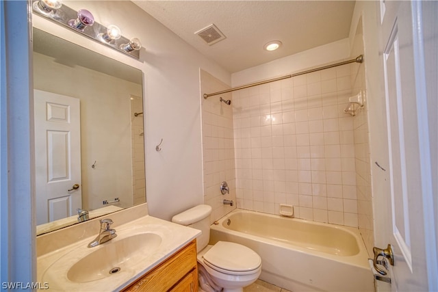 full bathroom featuring a textured ceiling, vanity, tiled shower / bath combo, and toilet