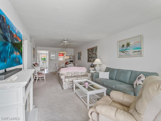 carpeted living room with ceiling fan and a textured ceiling