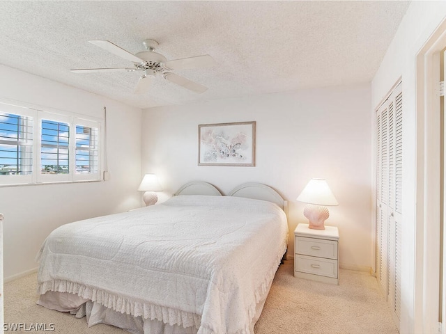 carpeted bedroom featuring ceiling fan, a textured ceiling, and a closet