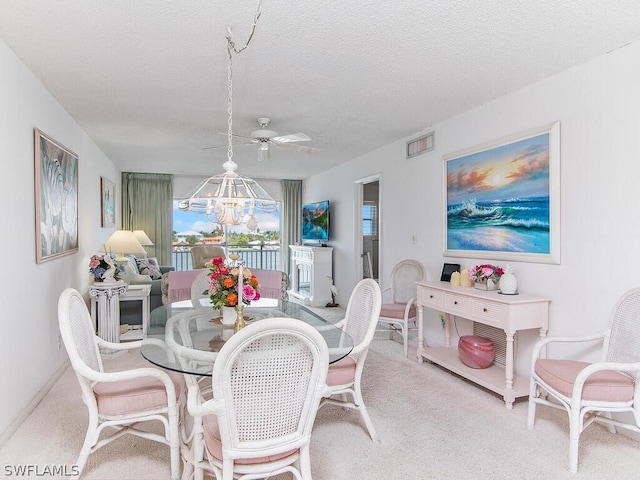 dining area with ceiling fan with notable chandelier, a textured ceiling, and light colored carpet