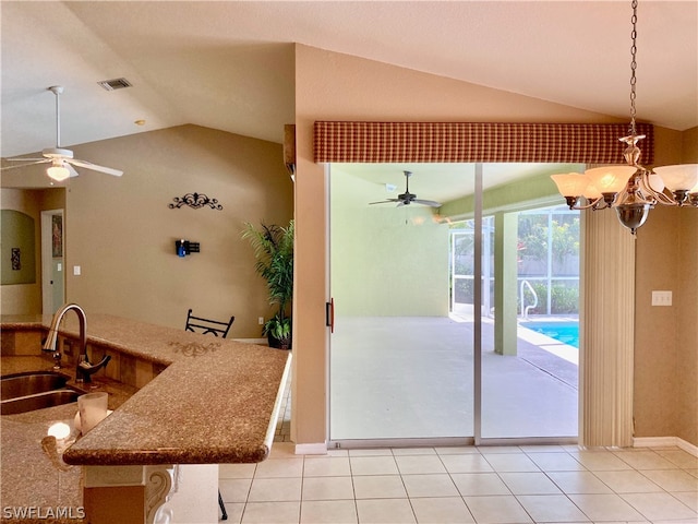 interior space featuring sink, hanging light fixtures, ceiling fan with notable chandelier, lofted ceiling, and light tile patterned flooring