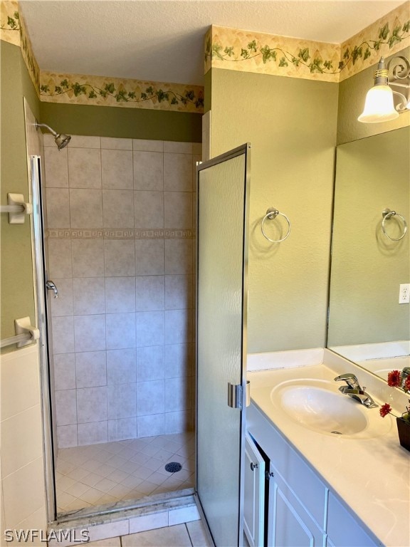 bathroom featuring vanity, walk in shower, a textured ceiling, and tile patterned flooring