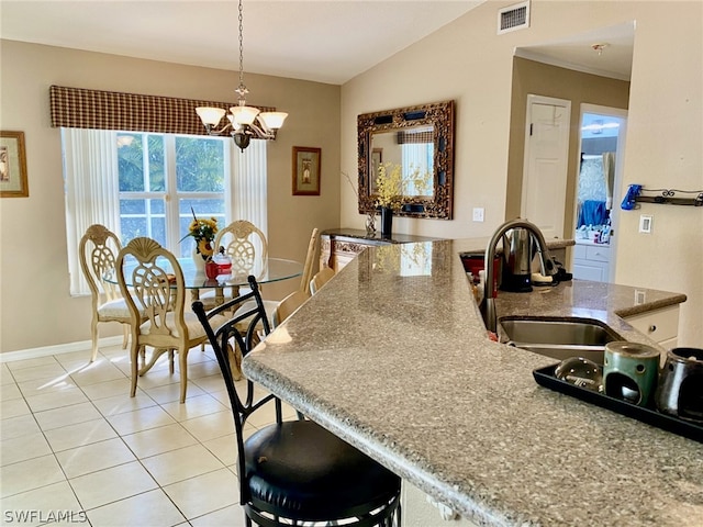 kitchen with light tile patterned flooring, lofted ceiling, an inviting chandelier, pendant lighting, and sink