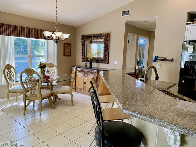 tiled dining area with a chandelier, vaulted ceiling, and sink