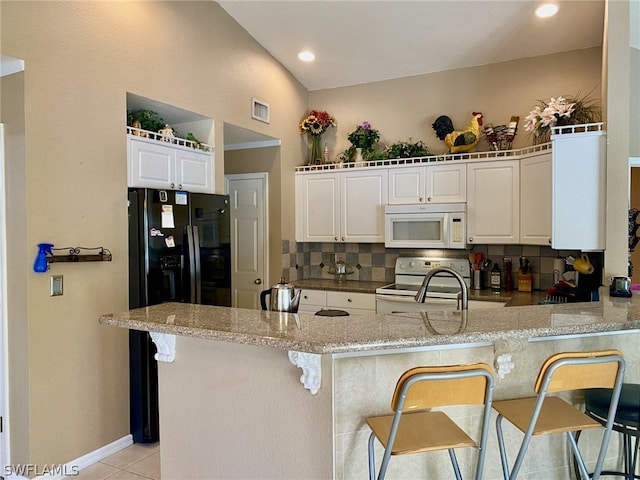 kitchen featuring white cabinetry, white appliances, a kitchen bar, kitchen peninsula, and backsplash