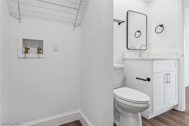 half bathroom featuring toilet, baseboards, wood finished floors, and vanity