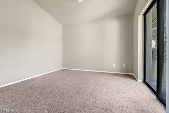 carpeted spare room featuring vaulted ceiling