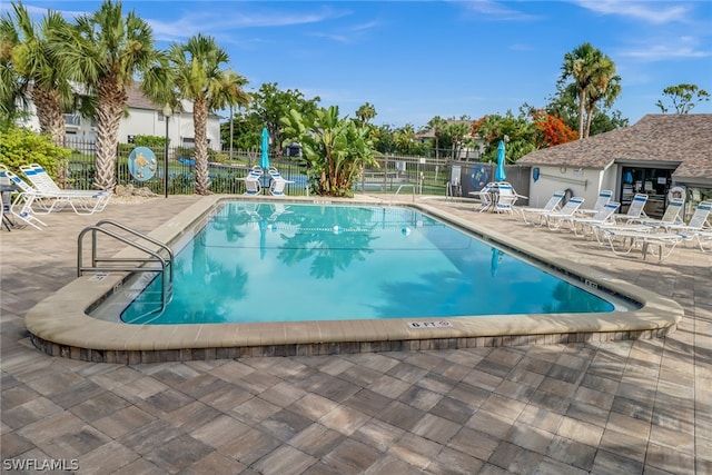 community pool with a patio and fence