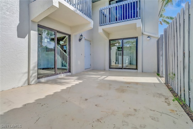 view of exterior entry featuring fence, a patio, and stucco siding