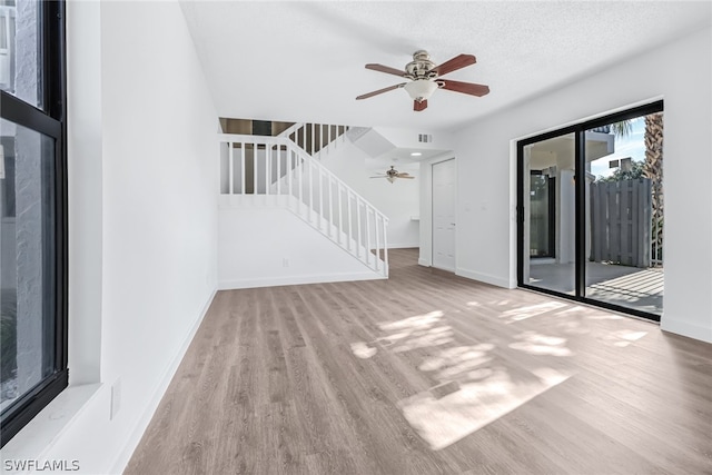 unfurnished living room featuring wood-type flooring, ceiling fan, and a textured ceiling