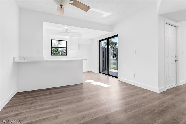 unfurnished living room with hardwood / wood-style floors, ceiling fan, and a textured ceiling