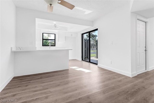 unfurnished living room with baseboards, a ceiling fan, and wood finished floors