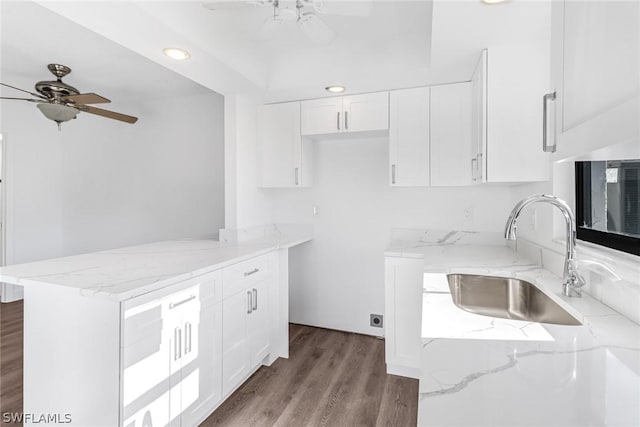 kitchen with a sink, ceiling fan, and light stone countertops