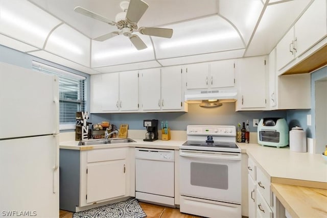 kitchen with white appliances, white cabinets, light countertops, under cabinet range hood, and a sink