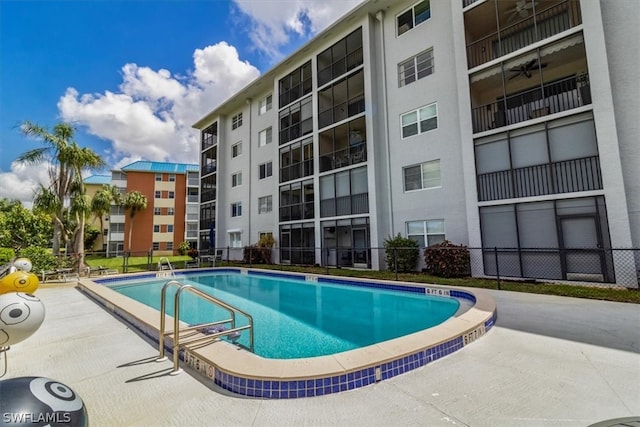 community pool with a patio area and fence