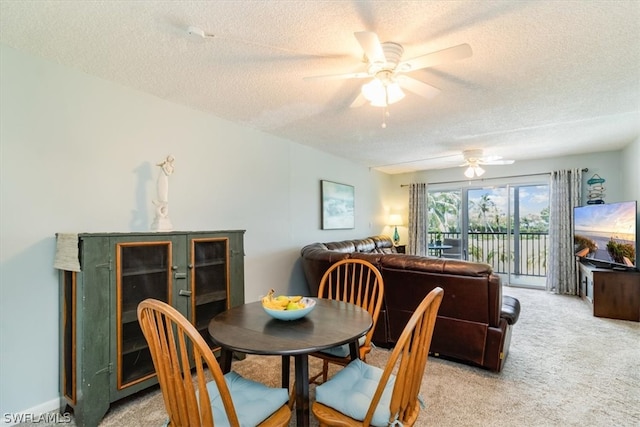 dining space featuring a textured ceiling, light colored carpet, and ceiling fan