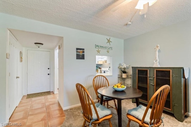 dining area featuring light colored carpet, light tile patterned flooring, ceiling fan, a textured ceiling, and baseboards