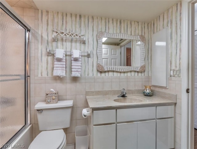 full bathroom featuring vanity, shower / bath combination with glass door, decorative backsplash, toilet, and tile walls