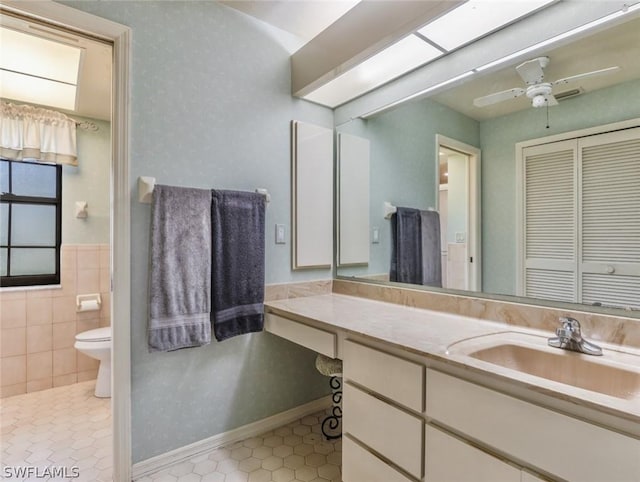 bathroom with tile patterned floors, vanity, ceiling fan, tile walls, and toilet