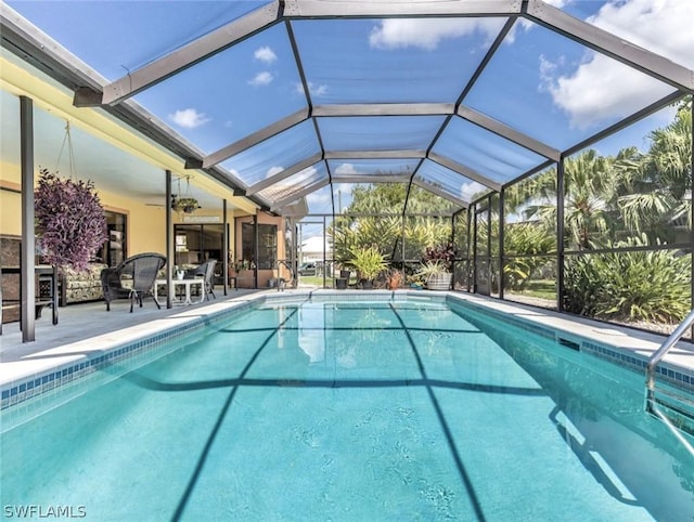 view of pool featuring glass enclosure, ceiling fan, and a patio area