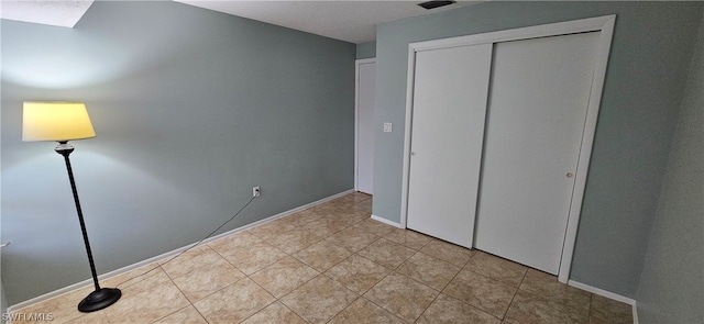 unfurnished bedroom featuring a closet and light tile floors