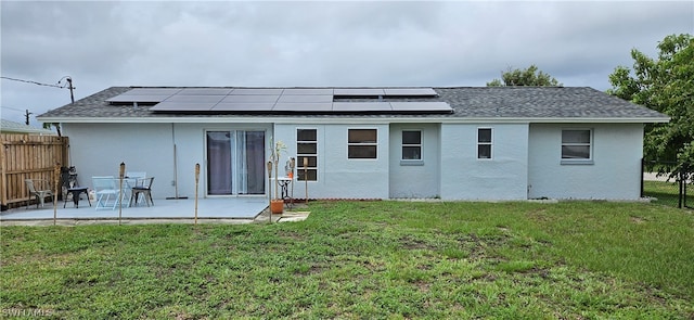 rear view of property with a yard, a patio area, and solar panels