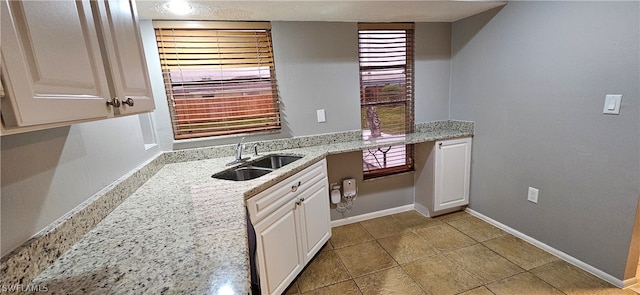 kitchen with plenty of natural light, sink, white cabinets, and light tile floors