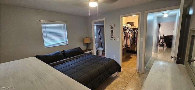 tiled bedroom with ceiling fan, a closet, ensuite bath, and a spacious closet