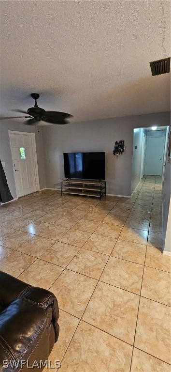 unfurnished living room with a textured ceiling, ceiling fan, and light tile floors