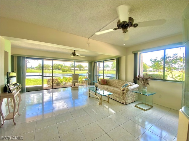 unfurnished living room featuring ceiling fan, light tile patterned floors, and a textured ceiling