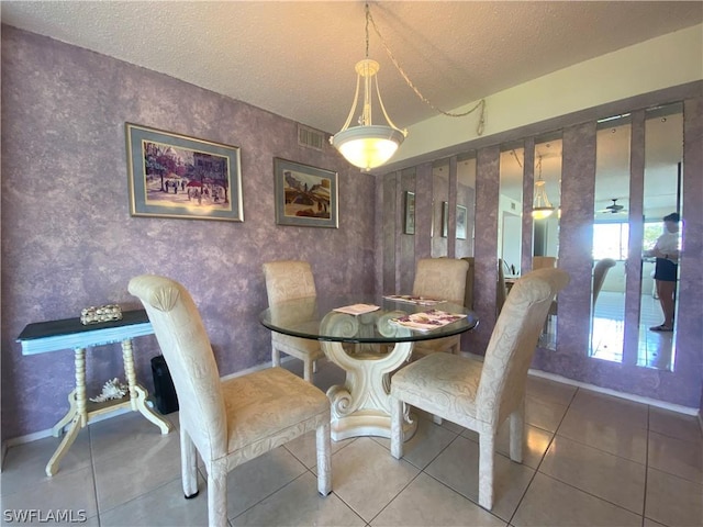 dining area featuring a textured ceiling, tile patterned flooring, visible vents, and baseboards