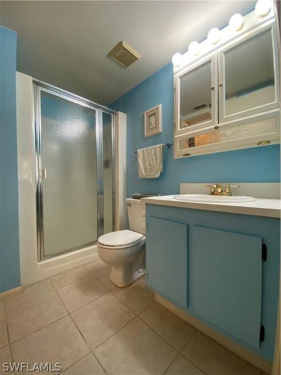 bathroom with a stall shower, vanity, toilet, and tile patterned floors