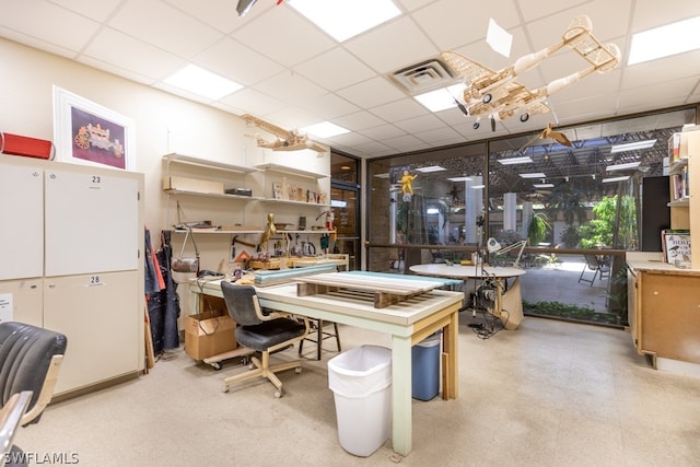 office space featuring a paneled ceiling, visible vents, tile patterned floors, and a workshop area