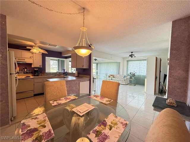 dining space with light tile patterned floors, a textured ceiling, visible vents, and a ceiling fan