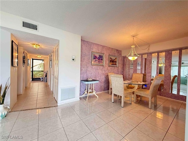 dining area featuring light tile patterned floors, a textured ceiling, baseboards, and visible vents