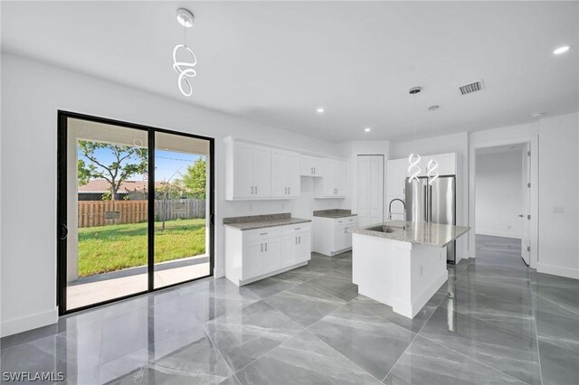 kitchen featuring a center island with sink, white cabinets, sink, and pendant lighting