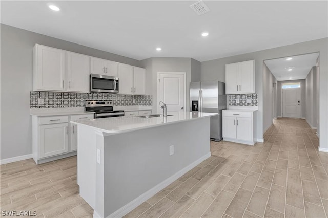 kitchen with sink, light hardwood / wood-style flooring, an island with sink, white cabinetry, and stainless steel appliances