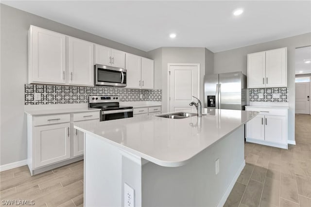 kitchen featuring stainless steel appliances, white cabinetry, a kitchen island with sink, and sink