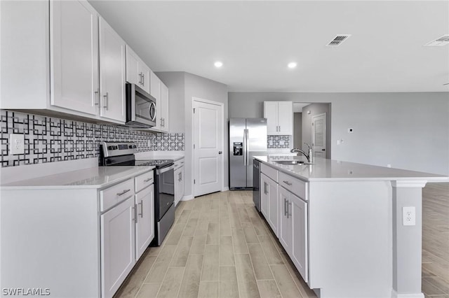 kitchen with a center island with sink, white cabinetry, sink, and appliances with stainless steel finishes