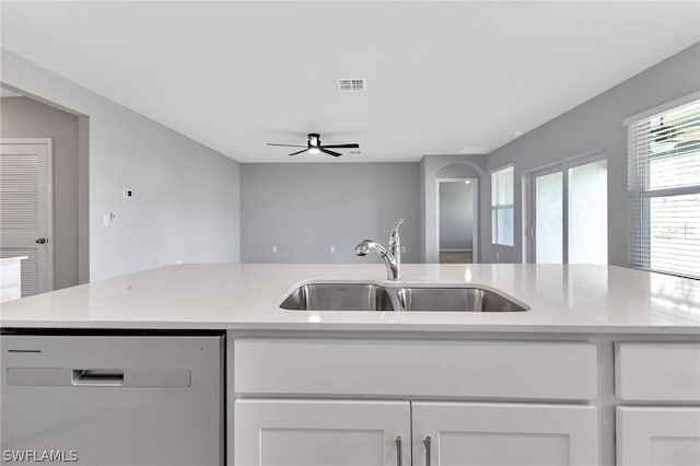 kitchen featuring ceiling fan, sink, stainless steel dishwasher, an island with sink, and white cabinets