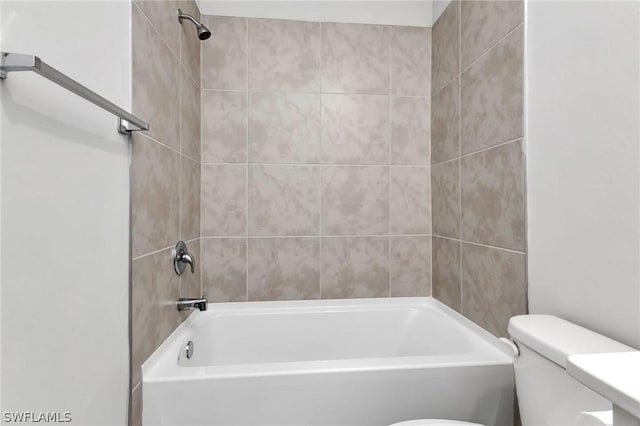 bathroom featuring tiled shower / bath combo and toilet