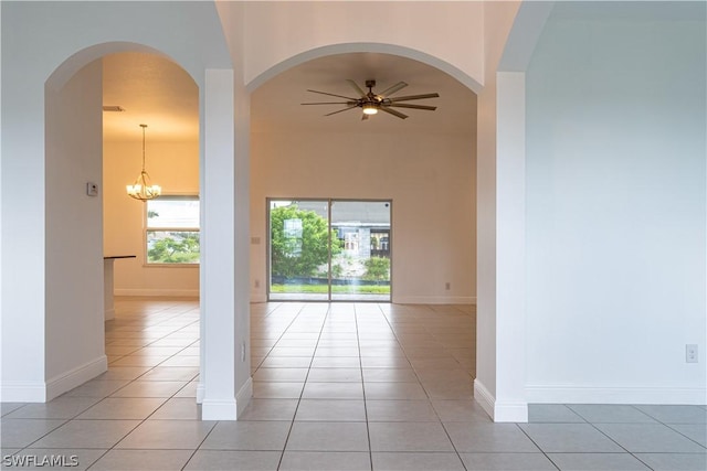 unfurnished room featuring ceiling fan with notable chandelier and light tile patterned floors